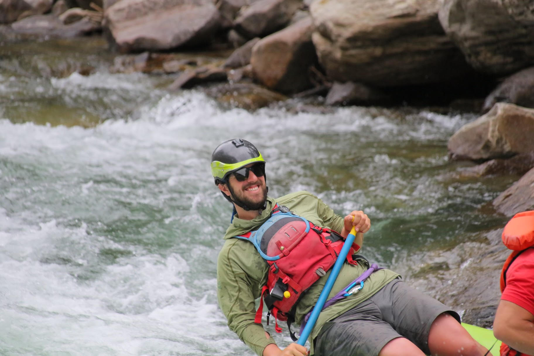 man smiling while guiding a raft